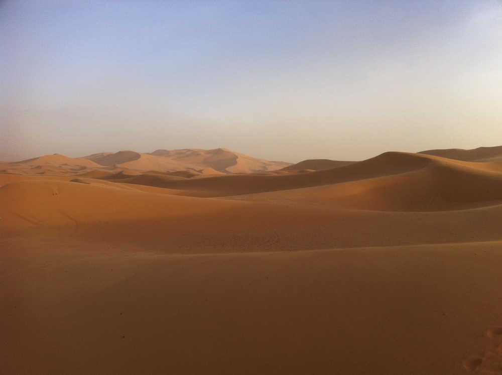Weite Sanddünenlandschaft der Sahara in Marokko bei warmem Licht