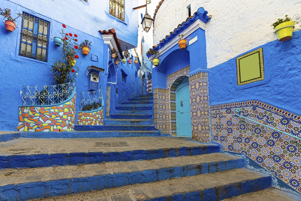 Blau gestrichene Gasse mit Treppen, Türen und Fliesenmustern in Chefchaouen
